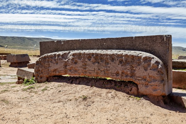 Ancient stone monument with mysterious engravings, lying under a cloudy sky in quiet surroundings, the archaeological site with the ruins of Tiwanaku in Bolivia