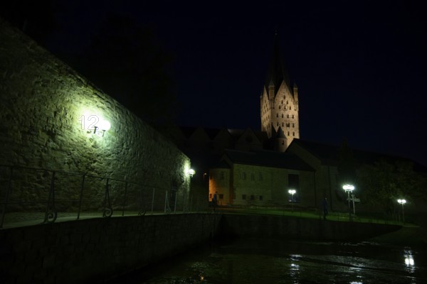 A Gothic church illuminated at night with illuminated tower and dark sky in the foreground the Kaiserpfalz, Paderborn, North Rhine-Westphalia, Germany