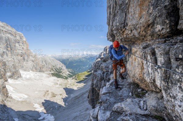 Mountaineers on a narrow band of rocks on the Via Ferrata Bocciere Centrale via ferrata, spectacular mountain landscape with steep rock faces, Brenta-Adamello Nature Park, Trentino, Italy