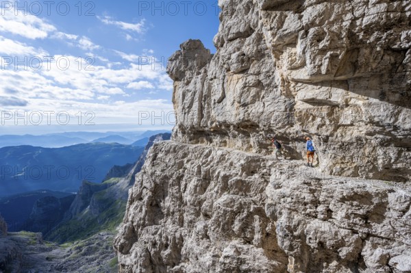 Two mountaineers on an exposed rock band in the secured via ferrata Bocciere Centrale, Brenta Mountains, Brenta-Adamello Natural Park, Trentino, Italy
