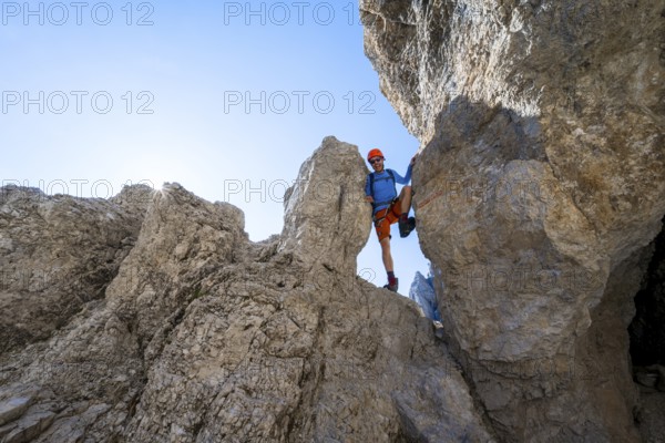 Mountaineers between rocks on the Via Ferrata Bocciere Centrale Via Ferrata, Sun Star, Brenta Mountains, Brenta-Adamello Natural Park, Trentino, Italy