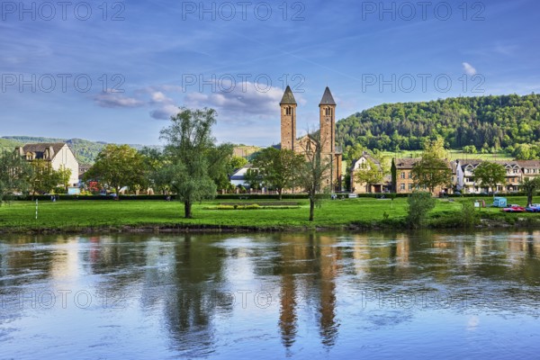 Moselle river, St. Salvator church, double tower, general architecture, houses, riverbank, hilly landscape, hills, forest, trees, meadow, abstract reflections on the water surface, blue sky, cumulus clouds, dramatic image processing, country road L98, Valwig, Cochem-Zell district, Rhineland-Palatinate, Germany