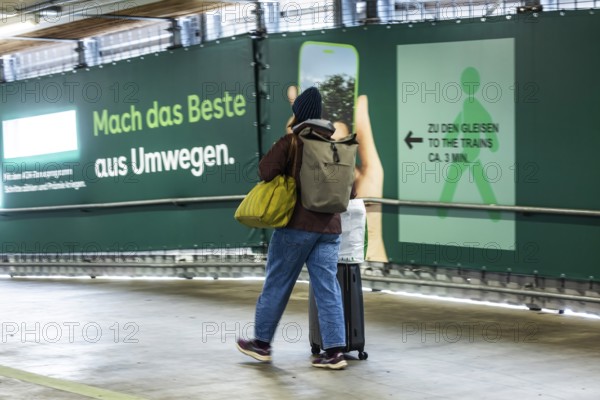 Construction work at Stuttgart Central Station as part of Stuttgart 21. Travelers have to accept long detours to get to the platform. Advertising banners on the makeshift footbridge refer to the detour through access to the tracks ridiculed as a long-distance hiking trail. Stuttgart, Baden-Württemberg, Germany