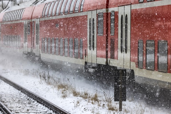 RegionalExpress RE on the road through a winter landscape in snowfall. A train on the line in the Deutsche Bahn AG rail network. Amstetten, Baden-Württemberg, Germany