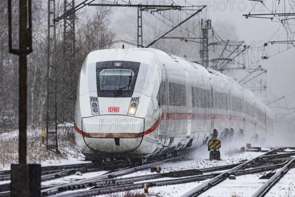 ICE traveling through a winter landscape in snowfall. A train on the line in the Deutsche Bahn Amstetten rail network, Baden-Württemberg, Germany
