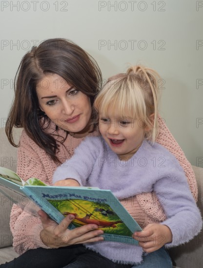 A mother reads a book together with her blonde girl, 4 years old, in Ystad, Skåne County, Sweden, Scandinavia