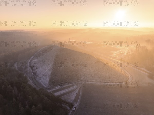 Landscaped hills in the pink-yellow light of sunrise, old deposit, construction site for PV open space plant, Lindenrain, Calw, Germany