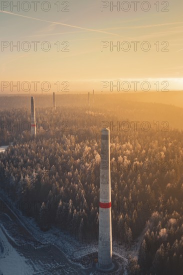 Wind turbine towers over a forest criss-crossed with snow trails, in warm sunlight, create a mystical landscape up to the horizon, Windkraft Bau, Besenfeld, Seewald, Freudenstadt district, Germany