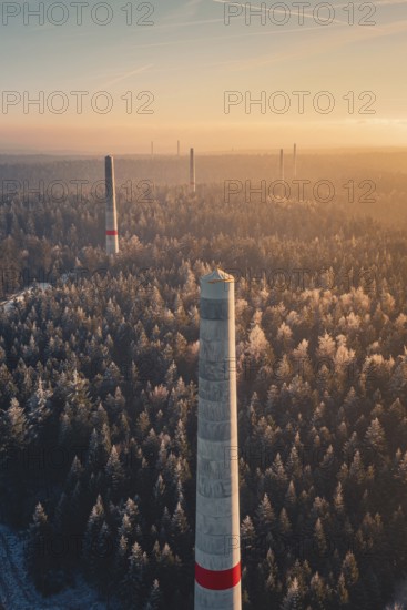 In the evening light, tall wind turbine towers with distinctive strips of red appear over a dense forest, surrounded by mysterious fog, Windkraft Bau, Besenfeld, Seewald, Freudenstadt district, Germany