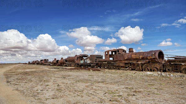 Row of abandoned, rusty locomotives in a desert-like environment, old rusty locomotives at the train cemetery near Uyuni in the Altiplano in Bolivia