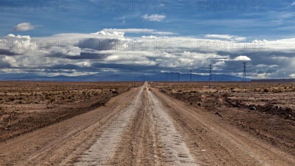 Lonely road stretching into the distance, under a cloudy sky, The landscape of the Altiplano near Uyuni in Bolivia
