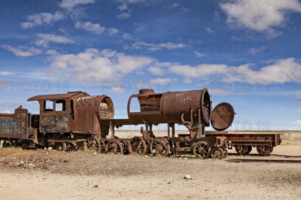 A heavily weathered locomotive with missing parts against a blue sky, old rusty locomotives at the train cemetery near Uyuni in the Altiplano in Bolivia