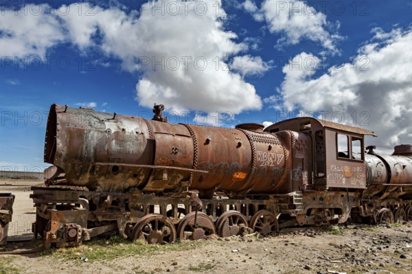 Rusty locomotive in a vast, cloudy and open landscape, old rusty locomotives at the train cemetery near Uyuni in the Altiplano in Bolivia