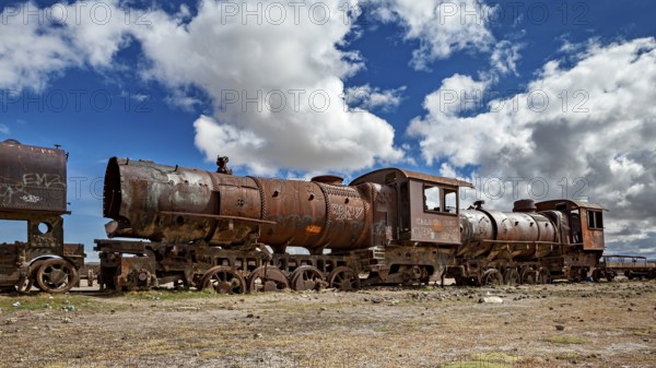 Abandoned, rusted locomotive in a dramatic cloudy landscape, old rusty locomotives at the train cemetery near Uyuni in the Altiplano in Bolivia