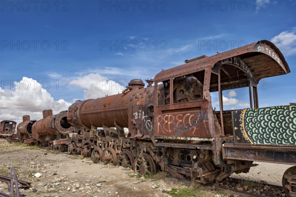 Close-up of a rusted locomotive with graffiti under a cloudy sky, old rusty locomotives at the train cemetery near Uyuni in the Altiplano in Bolivia