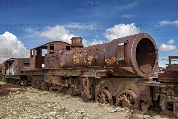 Rustic, graffiti-decorated locomotive in an open, cloudy landscape, old rusty locomotives at the train cemetery near Uyuni in the Altiplano in Bolivia