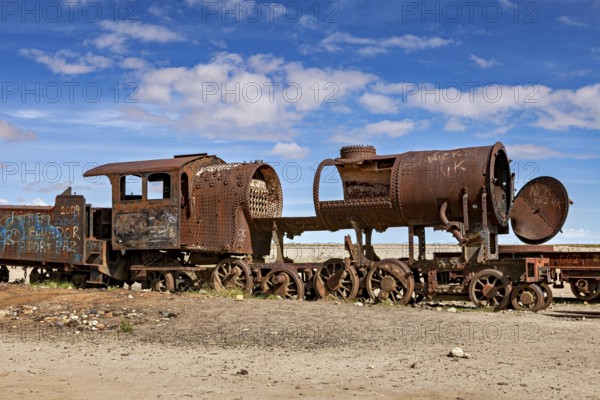 Rusty locomotive shows clear damage in an abandoned desert landscape, old rusty locomotives at the train cemetery near Uyuni in the Altiplano in Bolivia