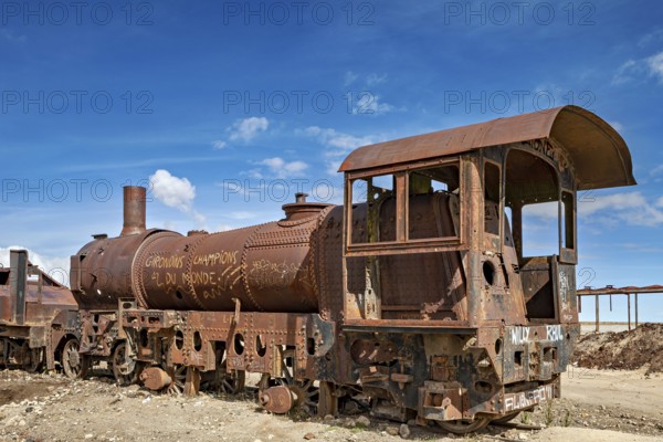 Rusted steam locomotive in an abandoned area under a blue sky, old rusty locomotives at the train cemetery near Uyuni in the Altiplano in Bolivia