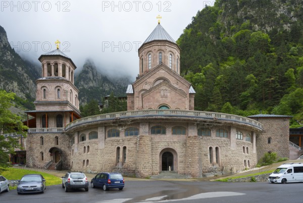 Historic monastery building surrounded by mountains and clouds in a peaceful atmosphere, Dariali monastery complex, located in the Dariali Gorge of the Tergi River, Terek, Khewi mountain region, Georgian military road, Mtskheta-Mtianeti province, High Caucasus, Georgia