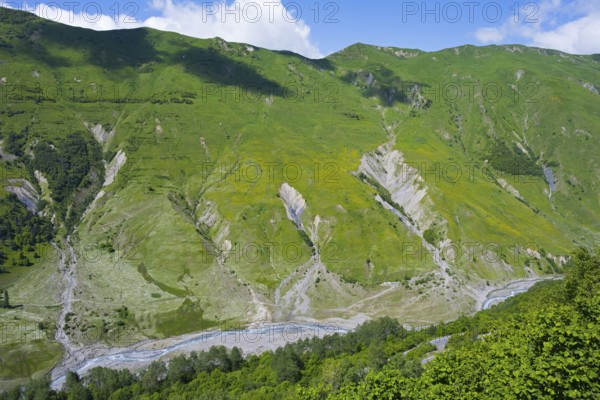 Green mountains and valleys with flowing river under blue sky, viewpoint near Gudauri, view of the mountainous landscape around Mleta, view of the White Aragvi River, Mtskheta-Mtianeti region, Georgian Military Highway, High Caucasus, Georgia