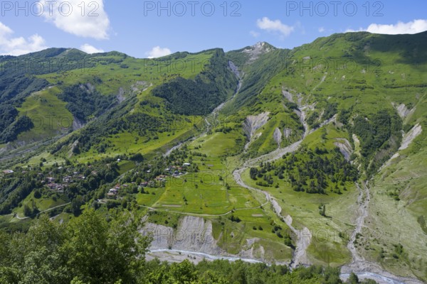 Green valley with mountains and river under blue sky and few clouds, viewpoint near Gudauri, view of the mountain landscape around Mleta, view of the White Aragvi river, Mtskheta-Mtianeti region, Georgian Military Highway, High Caucasus, Georgia, Asia