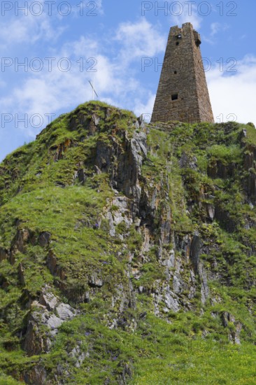 Historic ruin of a tower on a green rock face under a blue sky, Zion Tower, Sioni, Georgian Military Highway, Mtskheta-Mtianeti Province, High Caucasus, Georgia