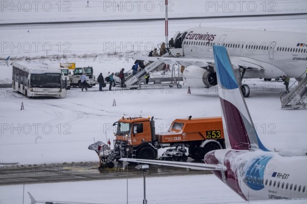 The onset of winter in North Rhine-Westphalia, flight operations are maintained at Düsseldorf airport with great effort, taxiways, passenger boarding, outdoor position, Eurowings, runway are freed from snow and ice with many clearing vehicles, airplanes are de-iced in front of takeoff, North Rhine-Westphalia, Germany