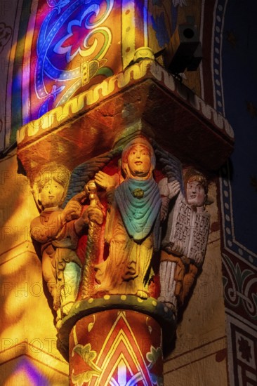 Issoire. Pillar (The Annunciation made to Mary) . The figures are illuminated by colorful light shining through a stained glass window inside Saint Austremoine Abbey, Puy de Dome, Auvergne Rhone Alpes, France