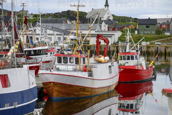 Fishing boats Fishing vessels are moored in Berlevag harbour in the north of the Varanger Peninsula with colorful buildings in the background, Berlevåg, Finnmark, Norway