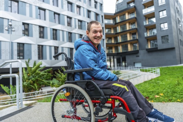 Happy man with a disability using a wheelchair on an accessible ramp in front of modern buildings, symbolizing inclusion, independent living, and urban accessibility for people with special needs