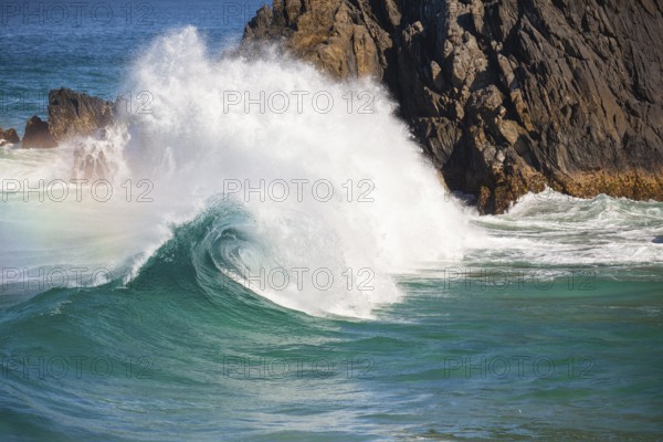 Waves crash against rocks at the mainland's easternmost point, creating rainbows in the ocean spray. Daylight, Byron Bay, New South Wales, Australia