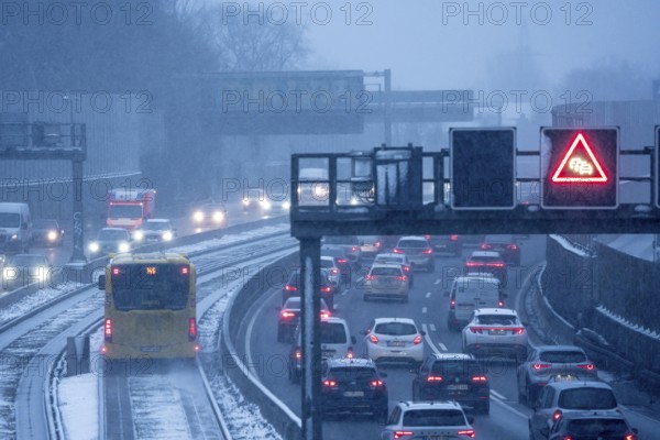 Winter weather, motorway traffic, A40 motorway, Ruhrschnellweg, in Essen, at the Essen-East motorway junction, snowfall, traffic jams, heavy flowing traffic, bus lane between roads, public transport, North Rhine-Westphalia, Germany