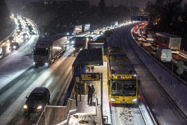 Winter weather, motorway traffic, A40 motorway, Ruhrschnellweg, in Essen, at the Essen-Ost motorway junction, snowfall, traffic jams, heavy flowing traffic, stop, bus lane between lanes, public transport, North Rhine-Westphalia, Germany