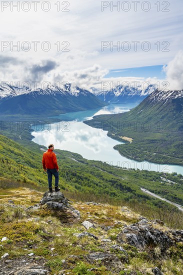 Climber enjoying the view, Slaughter Ridge Trail, view of snowy mountains and turquoise blue Kenai Lake, Cooper Landing, Kenai Peninsula, Alaska, USA