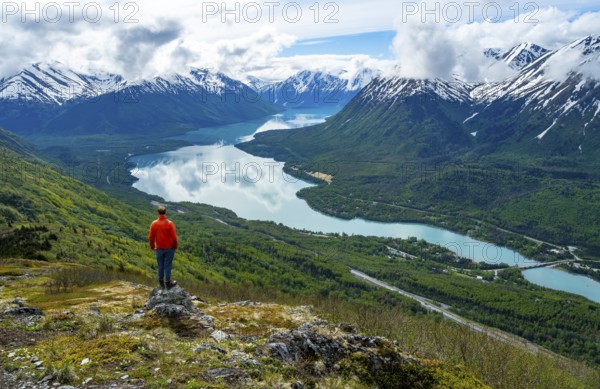 Climber enjoying the view, Slaughter Ridge Trail, view of snowy mountains and turquoise blue Kenai Lake, Cooper Landing, Kenai Peninsula, Alaska, USA