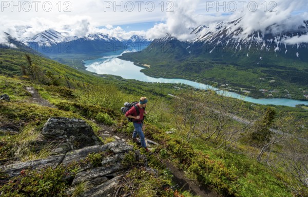 Climbers on a hiking trail, Slaughter Ridge Trail, view of snowy mountains and turquoise lake Kenai Lake, Cooper Landing, Kenai Peninsula, Alaska, USA