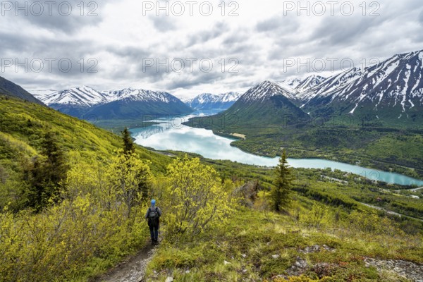 Climbers on a hiking trail, Slaughter Ridge Trail, view of snowy mountains in spring and turquoise blue Kenai Lake Lake, Cooper Landing, Kenai Peninsula, Alaska, USA