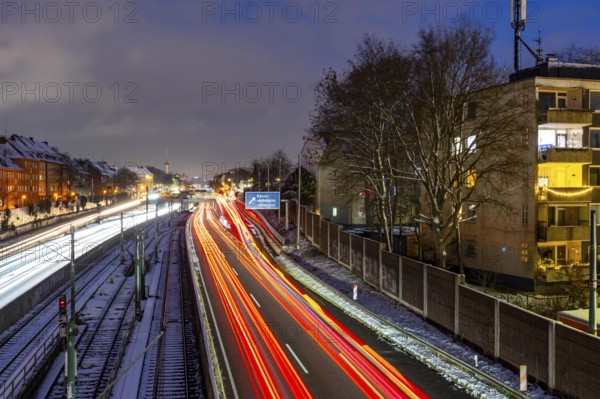 Autobahn A40, Ruhrschnellweg, near Essen at the Frohnhausen junction, evening traffic in winter, residential buildings directly on the 4-lane motorway, North Rhine-Westphalia, Germany