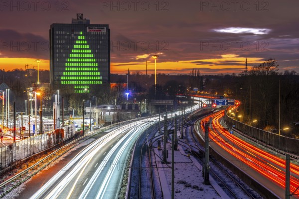 Autobahn A40, Ruhrschnellweg, between Essen and Mülheim an der Ruhr, evening traffic in winter, former, now vacant Stinnes high-rise building, at the Rhine-Ruhr Center, showing a green Christmas tree from illuminated windows at Christmas time, North Rhine-Westphalia, Germany