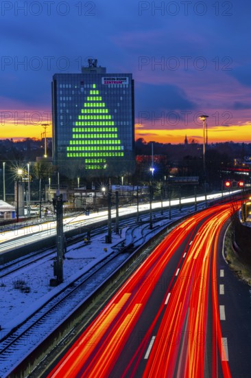 Autobahn A40, Ruhrschnellweg, between Essen and Mülheim an der Ruhr, evening traffic in winter, former, now vacant Stinnes high-rise building, at the Rhine-Ruhr Center, showing a green Christmas tree from illuminated windows at Christmas time, North Rhine-Westphalia, Germany
