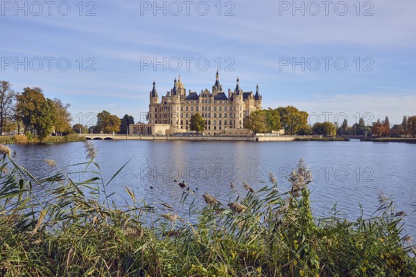 Castle, lake Burgsee, reed (Phragmites australis), trees, bushes, car bridge and pedestrian bridge, water surface with small waves, blue sky, cumulus clouds, cirrostratus clouds, Schwerin, state capital, independent city, Mecklenburg-Vorpommern, Germany
