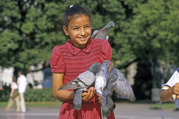 A girl holding two doves and feeding them, Placa de Catalunya, Barcelona, Spain, June 1999, vintage, retro, old, historic
