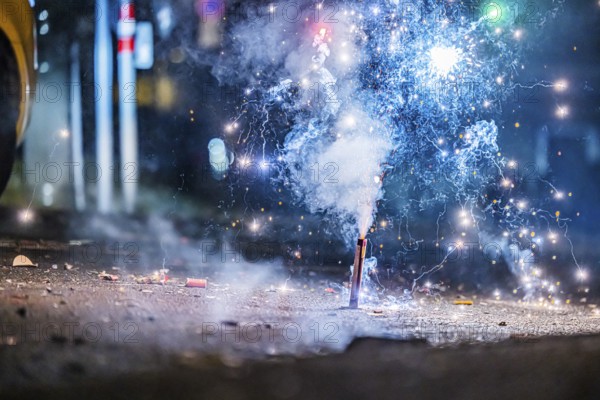 Burnt off fireworks are lying on the street, firecracker smoke produces smoke. New Year's night on a street in Stuttgart, Baden-Württemberg, Germany