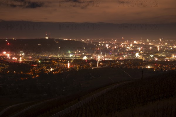 View from Kapellberg near Fellbach across the Neckar Valley to Stuttgart on New Year's Eve from 2025 to 2026. The television tower on the horizon as firecrackers and rockets light up the night sky at the turn of the year and greet the new year