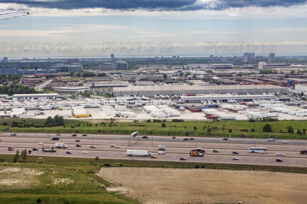 An industrial cityscape with a busy highway and overlying clouds, view from an airplane of the suburbs of Toronto in Canada