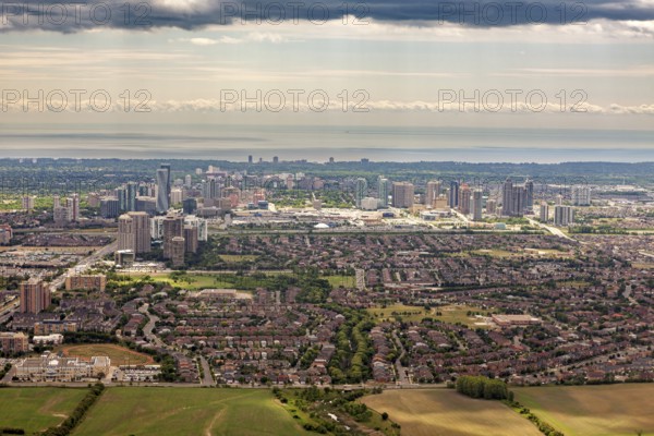 A comprehensive panorama of a city with high-rise buildings and suburbs under a cloudy sky, near the coast, view from an airplane of the suburbs of Toronto in Canada