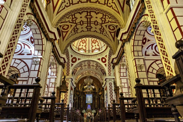 Sumptuous church interior with ornate ceilings and red patterns, The Basilica of St. Francis in downtown Lima in Peru