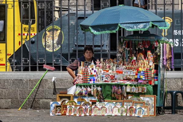 A woman sells colorful souvenirs at a street stand in a city with a bus in the background, a woman with her small street shop in downtown Lima in Peru