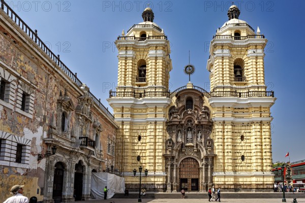 Baroque church with yellow façade and two towers in a sunny atmosphere, The Basilica of St. Francis in downtown Lima in Peru