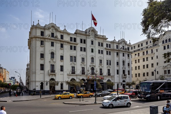 Large white building with national flag surrounded by vehicles and trees, Downtown Lima in Peru